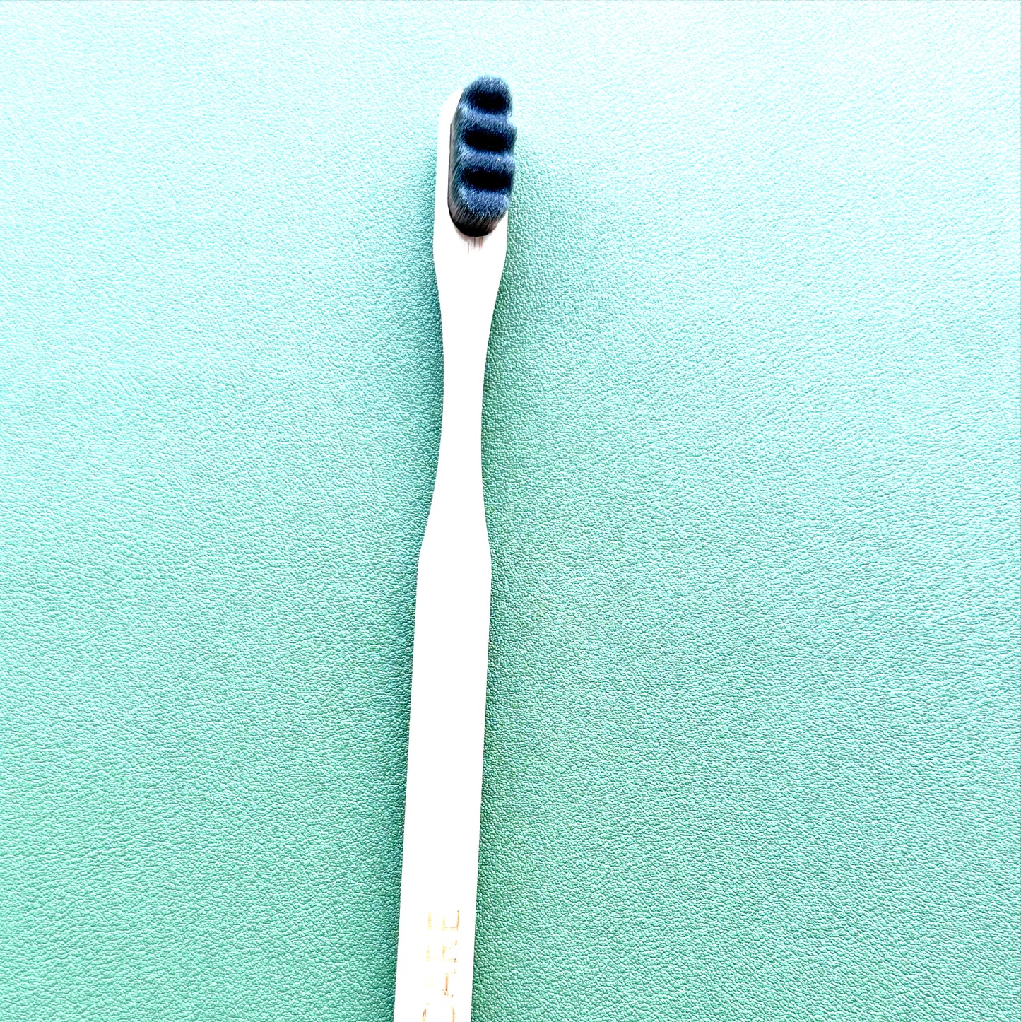 Gray toothbrush with blue bristles on a green background