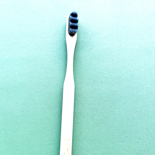 Gray toothbrush with blue bristles on a green background